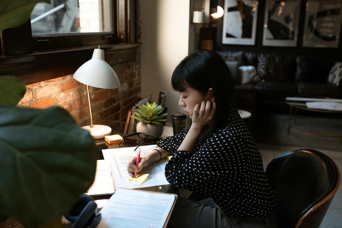 Woman writing on a sticky note working from home