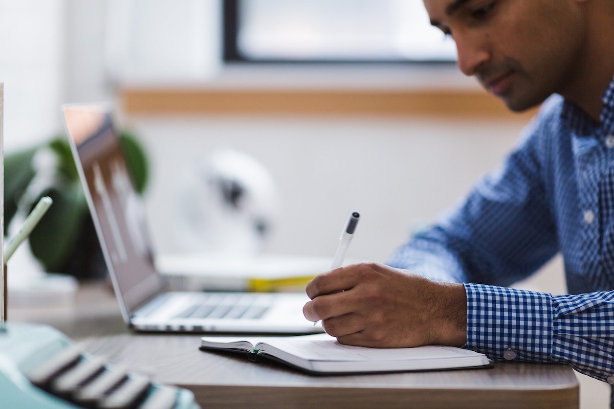 A man writing and studying at his laptop