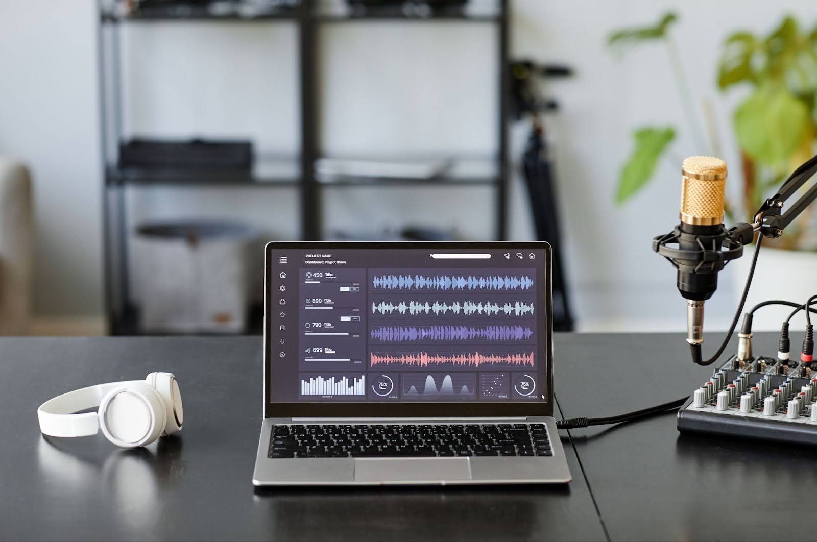 Image of podcast audio editing on a laptop with podcast equipment on a table