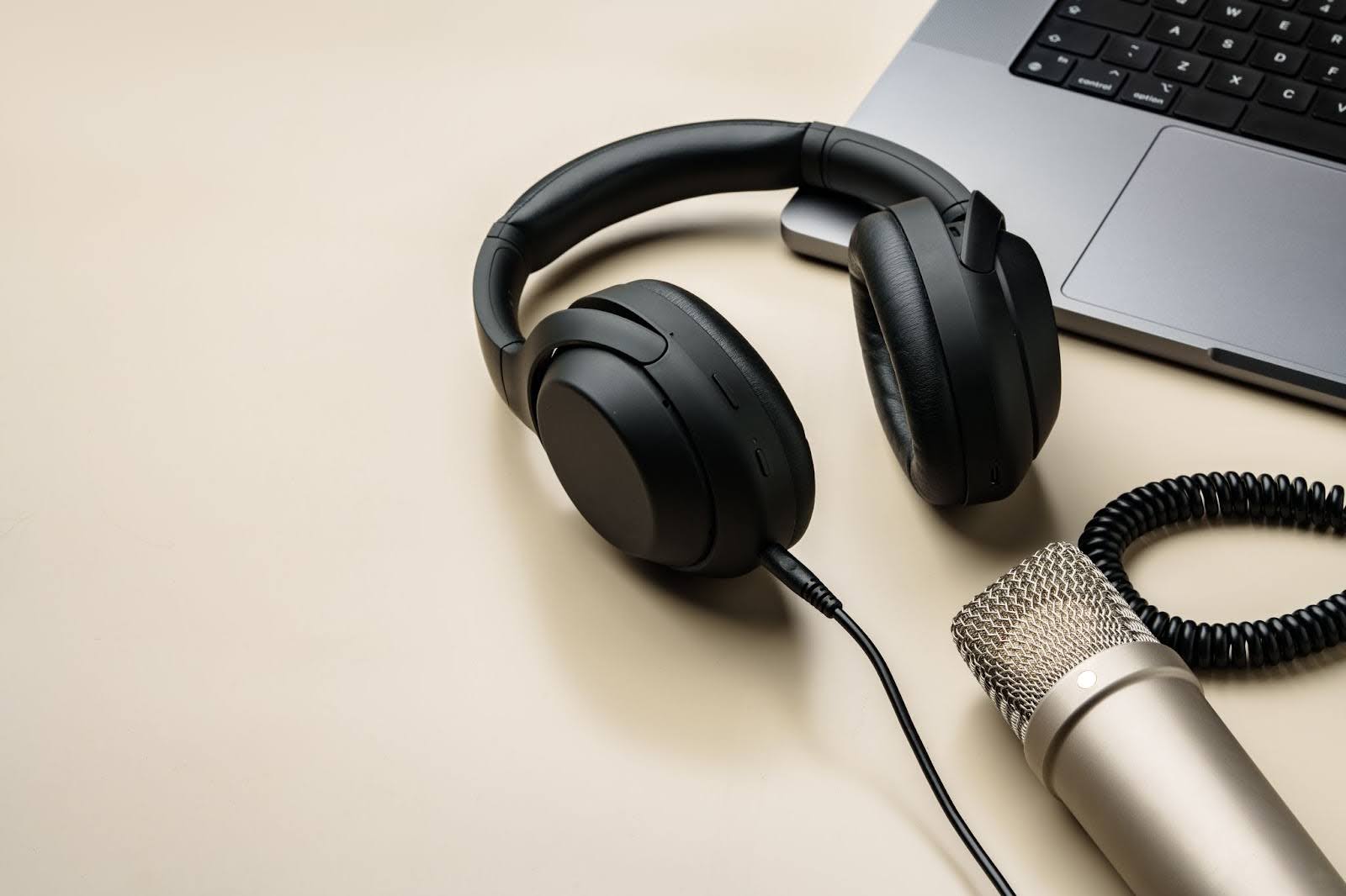 Image of headphones, a condenser microphone, and a laptop on a table