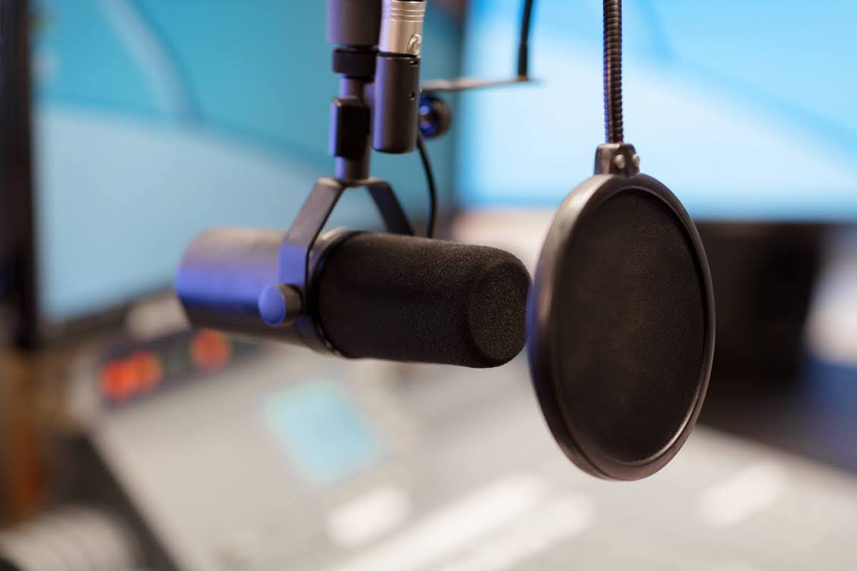 Close up image of a podcasting microphone with a pop shield