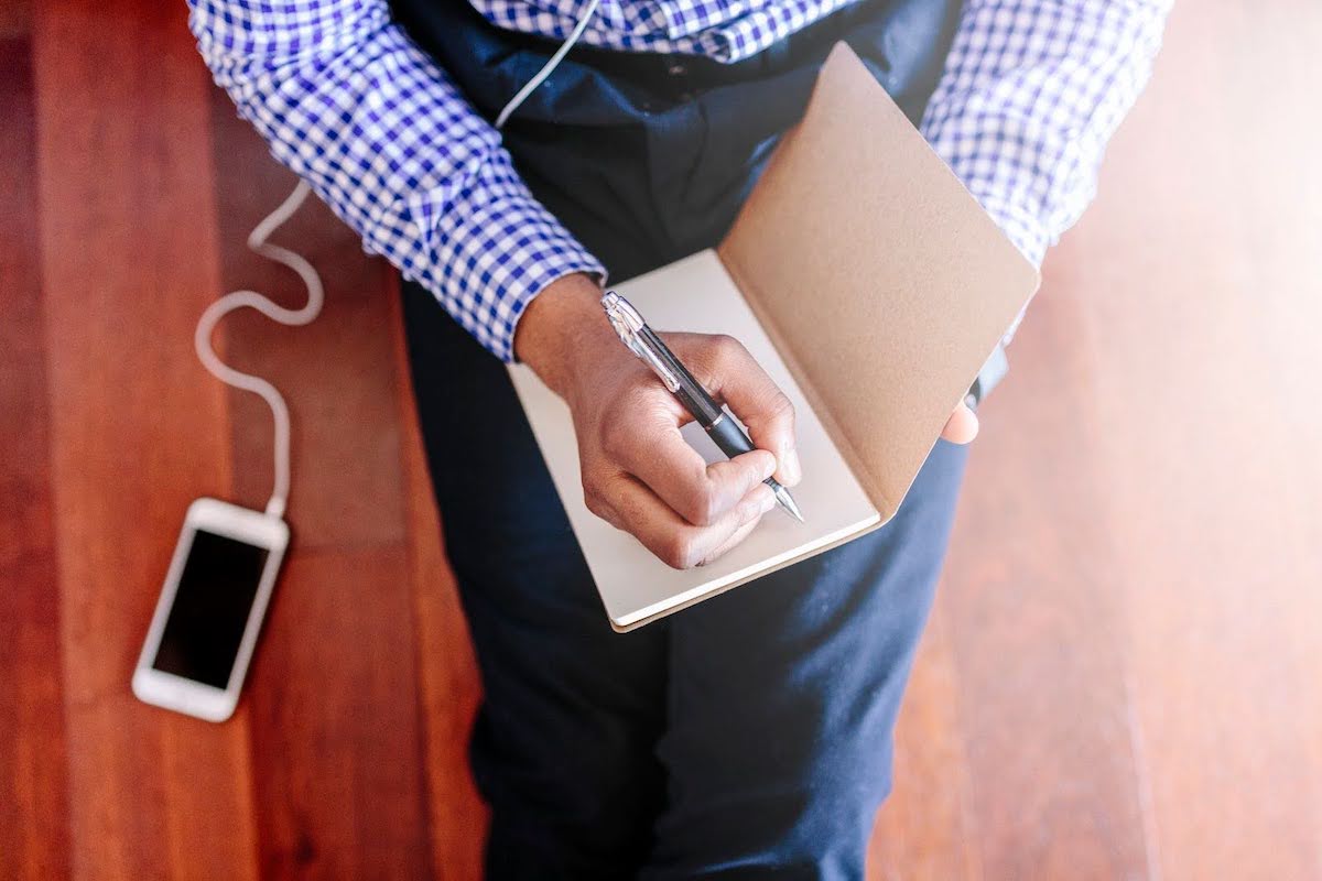 Image of a man writing in a blank notebook 