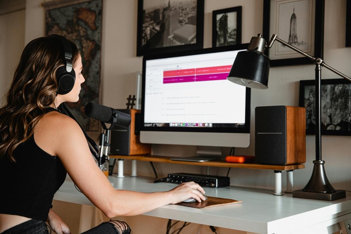 Woman in black top wearing black headphones in front of an apple mac