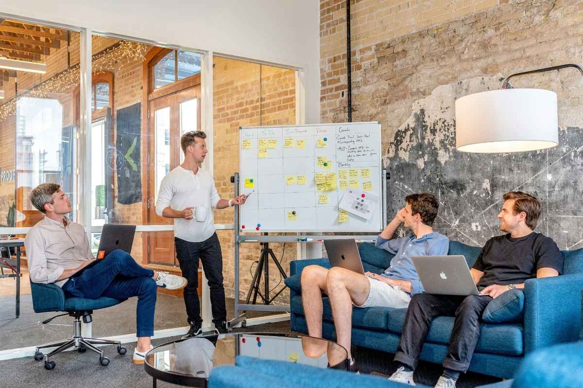 A group of people in a strategy meeting with laptops and a whiteboard