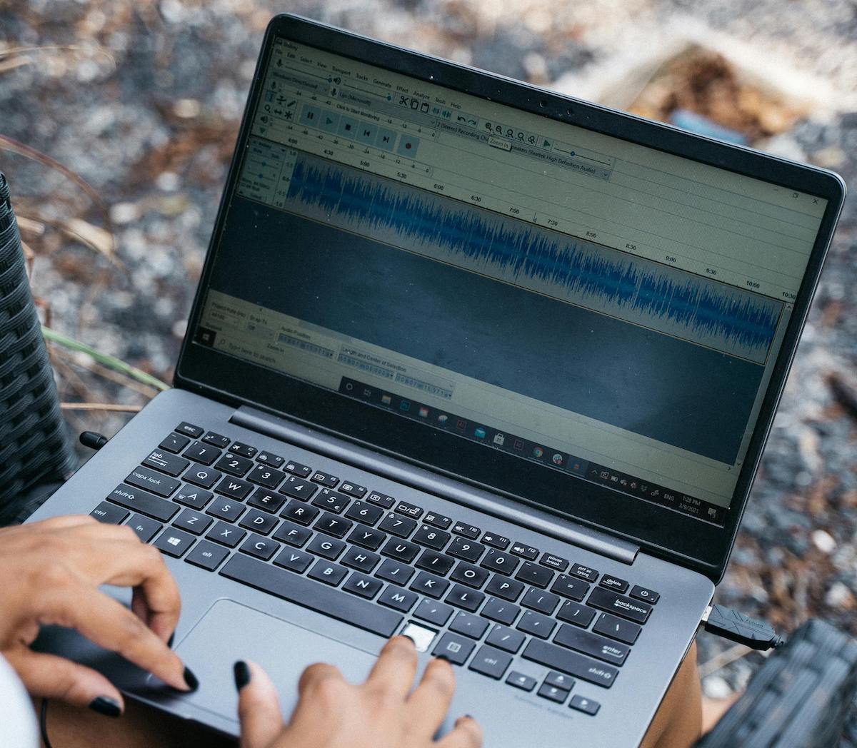 Woman With Black Nails Using Laptop Podcast Editing Software