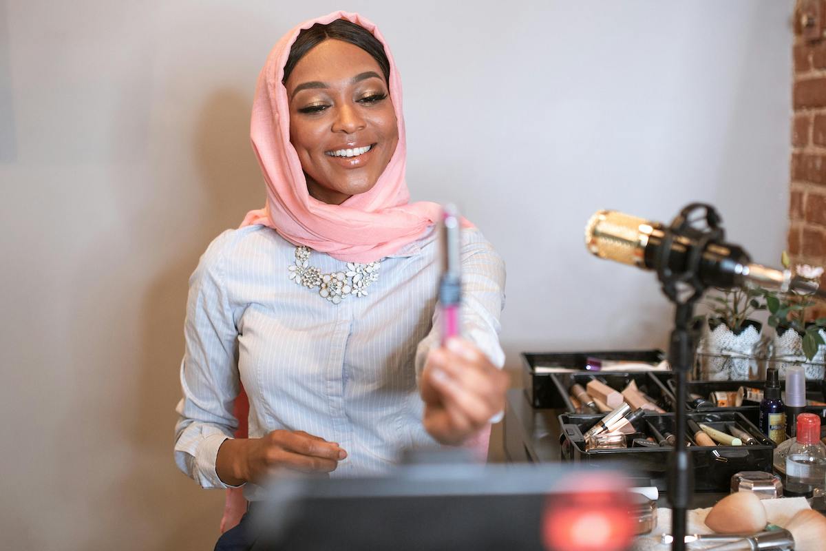 Woman with Pink Headscarf Holding a Cosmetic Product