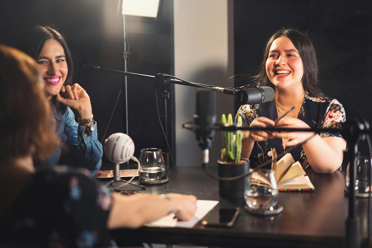 Podcast guests laughing with host at a table